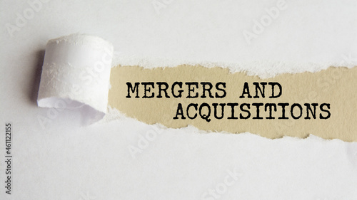 mergers and acquisitions. words. text on gray paper on torn paper background