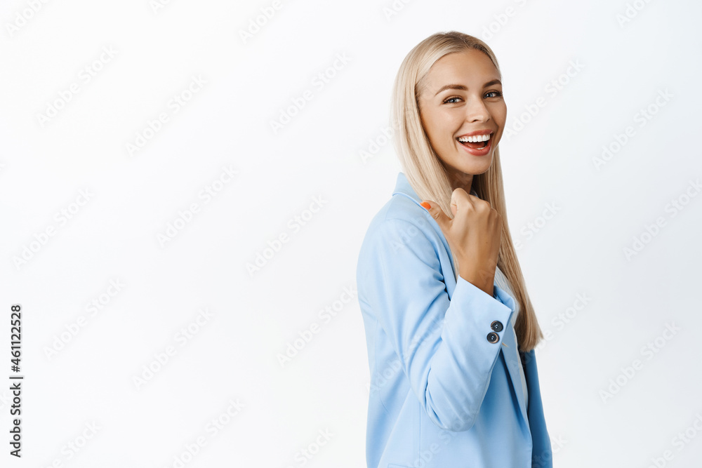 Portrait of smiling ambitious saleswoman pointing left, showing advertisement, company logo behind her back, standing over white background Portrait of smiling ambitious saleswoman pointing left, showing advertisement, company logo behind her back, standing over white background
