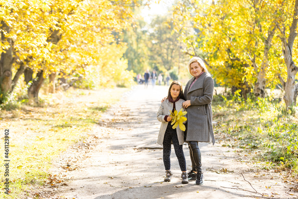 Obraz premium Young mother playing with her daughter in autumn park