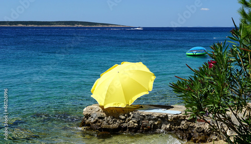 Yellow umbrella on a stone beach on a beautiful summer day photo