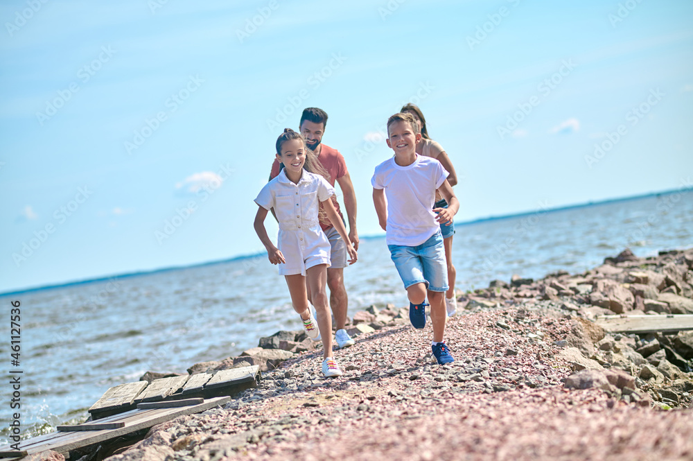 A happy family feeling excited and running on a beach A happy family feeling excited and running on a beach
