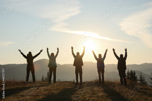 Group of people enjoying sunrise in mountains  back view