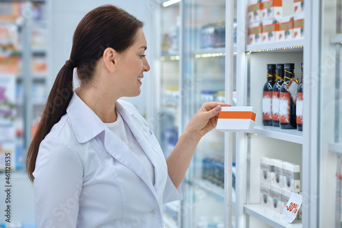 Profile of smiling woman with box of medicine