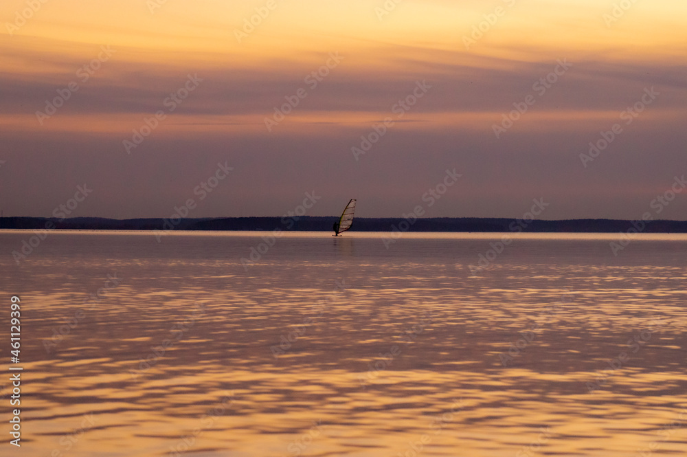 Beautiful sunset on the water at sunset with a sail on the horizon