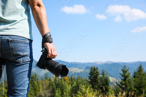 Professional photographer with modern camera in mountains, closeup. Space for text