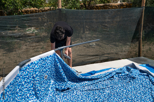 Emirdag, Turkey-July 22 2021: Man instals a plastic pool in the garden. photo