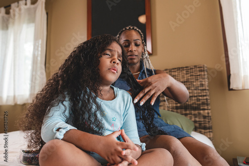 Konstfotografi Niña afroamericana haciendo un gesto de dolor mientras su mamá cepilla su cabell