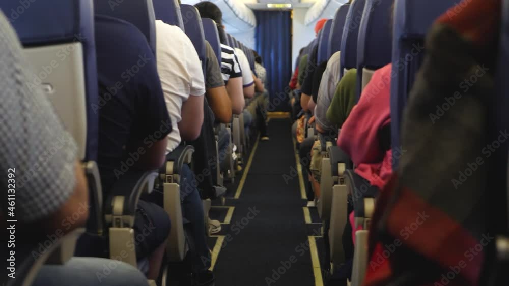 Unrecognizable passengers on seats in interior of airplane. View inside in plane. Long and boring fly. Economy lowcost flight in cabin. No social distance