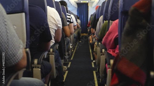 Unrecognizable passengers on seats in interior of airplane. View inside in plane. Long and boring fly. Economy lowcost flight in cabin. No social distance photo