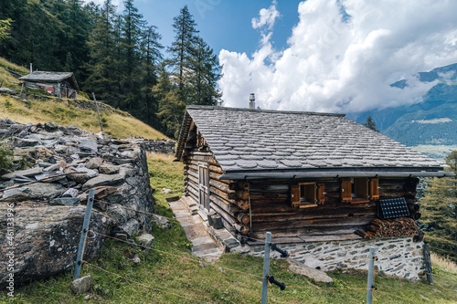 A wooden mountain hut or challet on a beautiful summer day. Blue sky, clouds, green pasture and mountain hut made of wood. photo