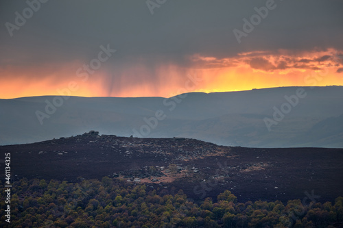 Rain falling on KinderScout at sunset over Over Owler Tor, Peak District, UK photo