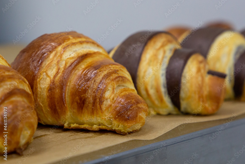 Many croissants with different flavors are freashly baked on the table. Manual production of handmade croissants and pastries
