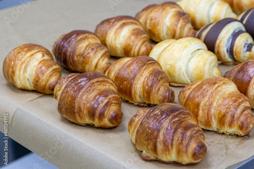 Many croissants with different flavors are arranged in dense rows on the table. Manual production of handmade croissants and pastries
