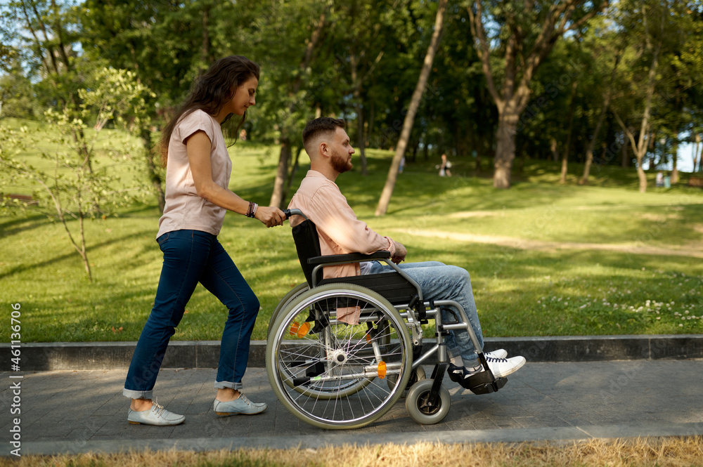 Young couple with wheelchair walking in the park Young couple with wheelchair walking in the park