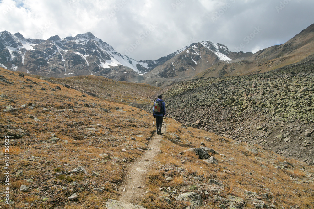 A tourist walks along a trail with a view of the Caucasus Mountains, Elbrus region, Russia.