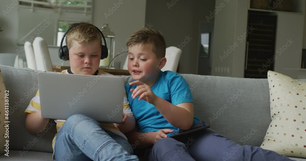 Caucasian boy with his brother sitting in living room and using laptop Caucasian boy with his brother sitting in living room and using laptop