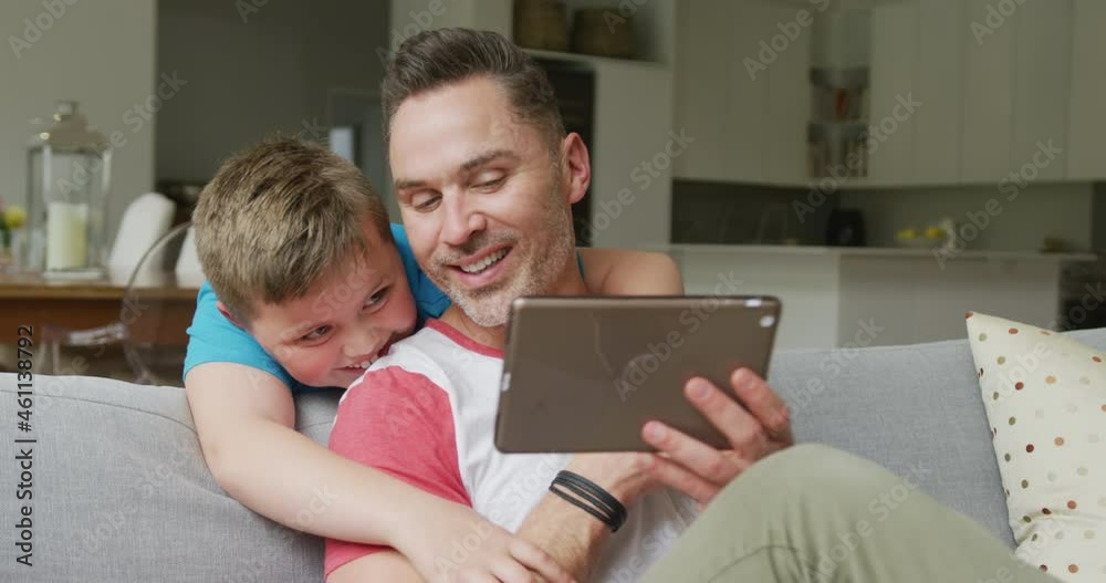 Happy caucasian father with son sitting in living room and using tablet Happy caucasian father with son sitting in living room and using tablet