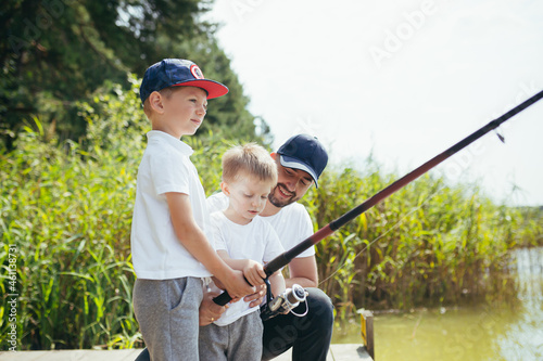 A father with two young sons fishes on the lake in the summer on weekends