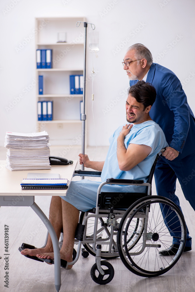 Young male employee in wheel-chair feeling bad at workplace Young male employee in wheel-chair feeling bad at workplace