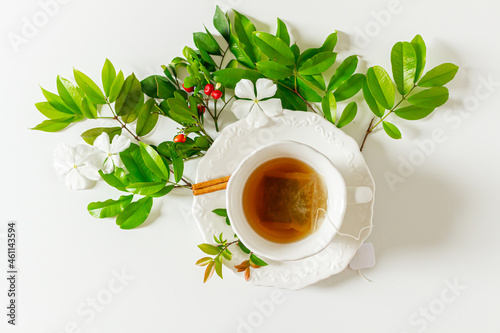 Cup of tea and plant leaves composition on white background. Flat lay, top view. 