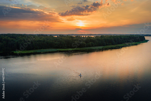 Fototapeta Naklejka Na Ścianę i Meble -  Man with stand up paddleboard in water during sunrise
