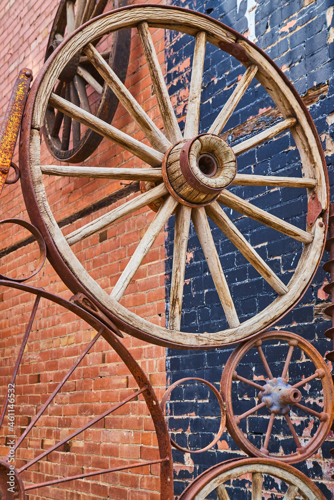 Old carriage wheels in collage against brick building