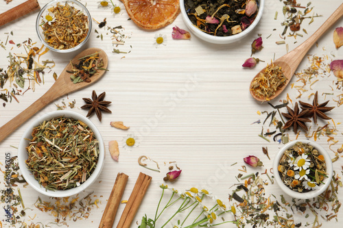 Frame of different dry teas on white wooden table, space for text