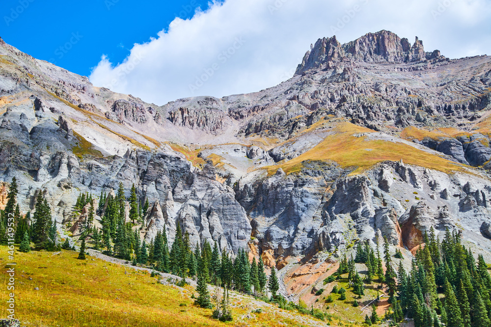 Obraz premium Mountain with columns of gray rock and sharp peaks with pine trees at base