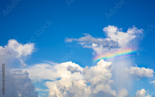 The white clouds have colorful rainbows in the bright blue sky in the daytime.