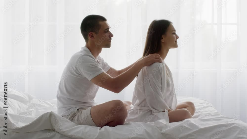 Caring man giving relaxing body massage to his wife in bed Caring man giving relaxing body massage to his wife in bed
