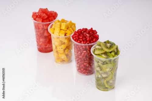 Watermelon , pineapple  , pomegrenate and Kiwi  Slices arranged  in two transparent glasses with white background, isolated