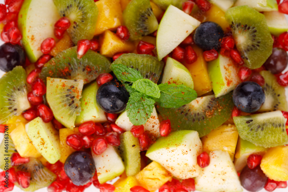 Mixed fruit salad arranged in a transparent rectangle tableware and garnished with mint leaf. Mixed fruit salad arranged in a transparent rectangle tableware and garnished with mint leaf.