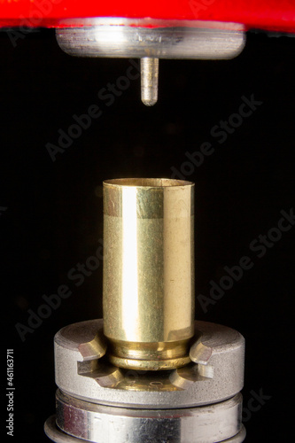 Reloading 9mm cartridge: decapping of brass casing with full length size die on press.