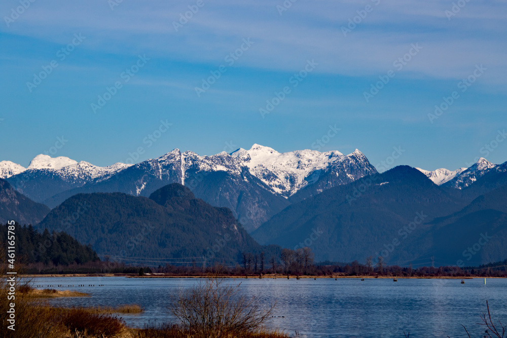 A view of a wide river with snow capped mountains in the background A view of a wide river with snow capped mountains in the background