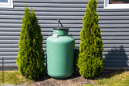 A large green propane tank on the side of a house