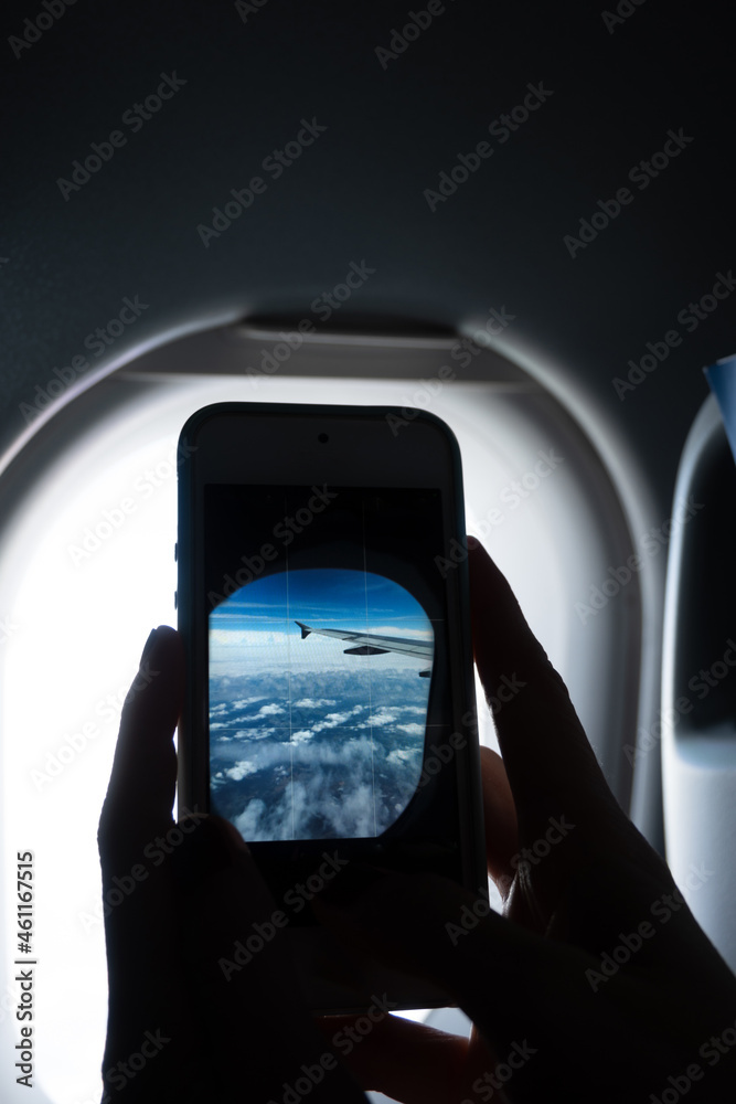 Person photographing an airplane window with a cell phone