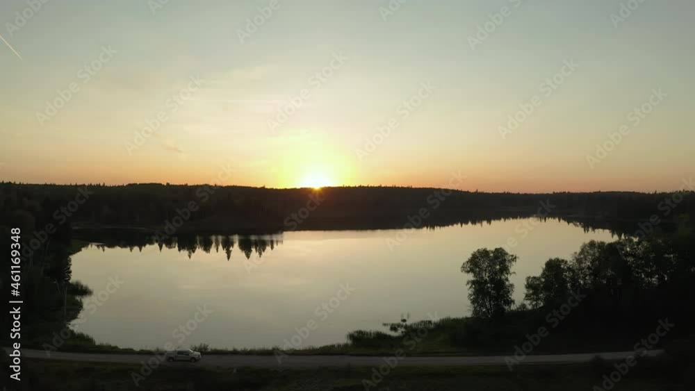 Aerial side view of white truck driving on rural road next to lake during sunset in Boreal forest, Saskatchewan, Canada Aerial side view of white truck driving on rural road next to lake during sunset in Boreal forest, Saskatchewan, Canada