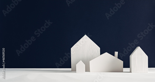 Little white wooden toy houses on a black background. Minimalist Scandinavian decorative design