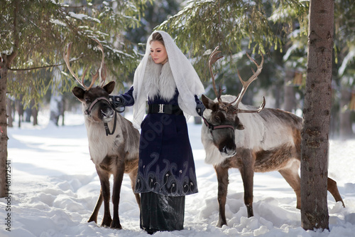 A girl walks in the winter with deer in the forest. Fairy tale. Reindeer. Fabulous photo session