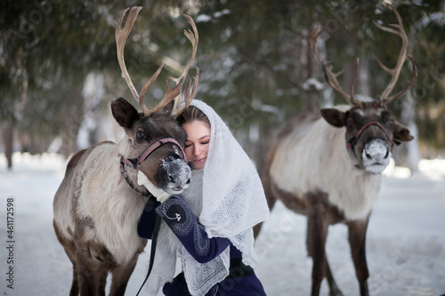 Fotografie A girl walks in the winter with deer in the forest