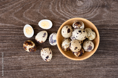 Boiled quail eggs in wooden bowl on wood table. top view
