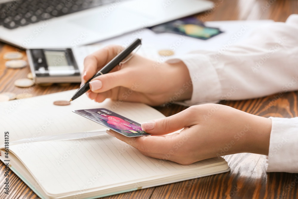 Businesswoman with credit card and notebook working in office Businesswoman with credit card and notebook working in office