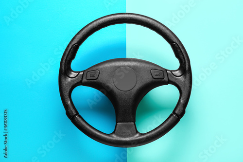 Black steering wheel on color background