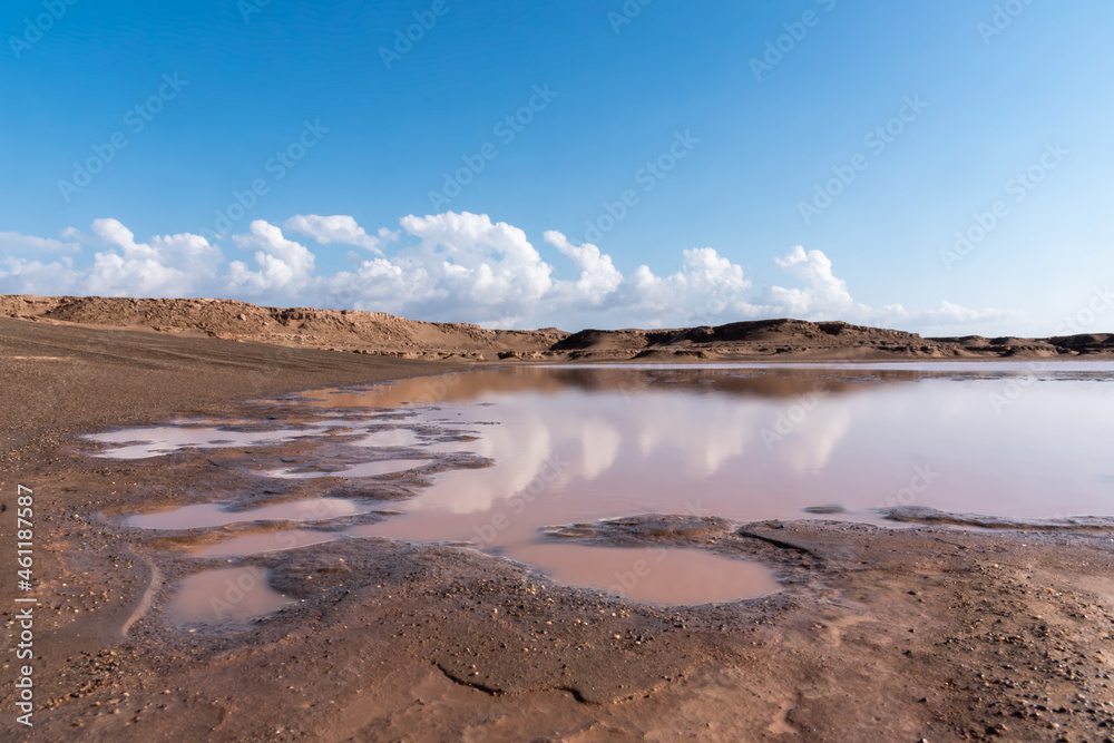 gathered water in a arid lake in dasht e lut or sahara desert with cloudy sky