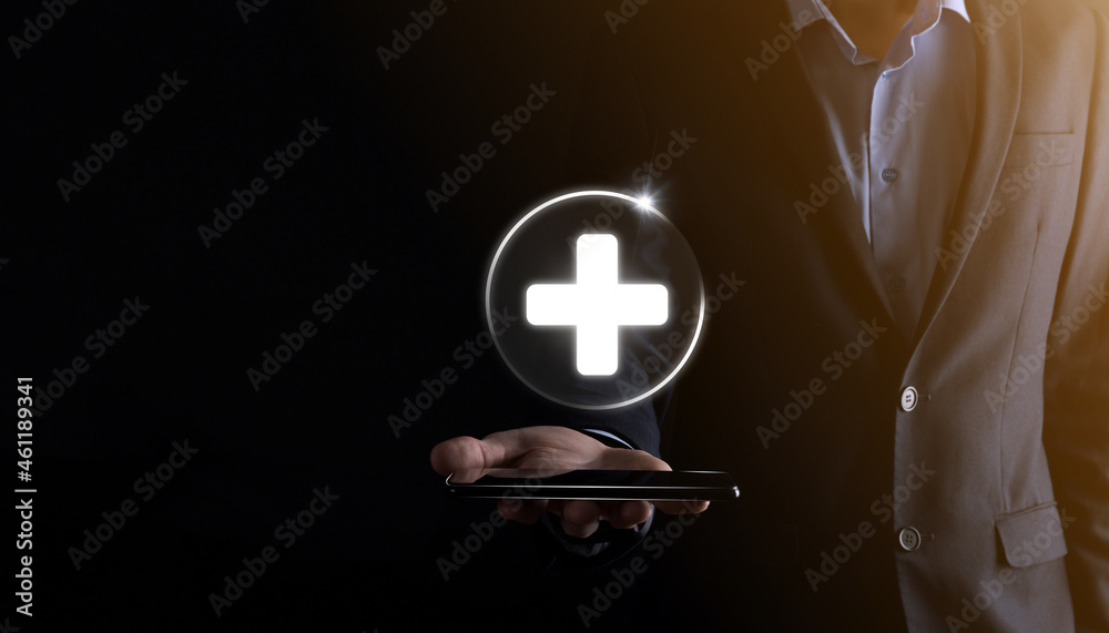 Obraz premium Businessman hold virtual plus medical network connection icons. Covid-19 pandemic develop people awareness and spread attention on their healthcare.