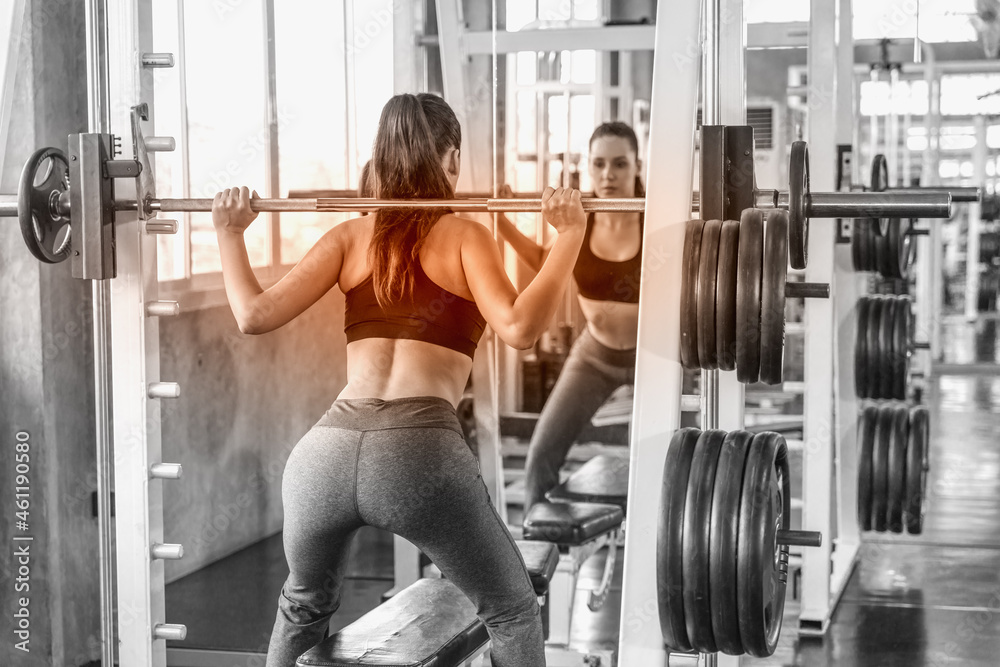athletic woman exercising with barbell lifting in gym and fitness club athletic woman exercising with barbell lifting in gym and fitness club