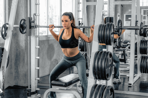 athletic woman exercising with barbell lifting in gym and fitness club