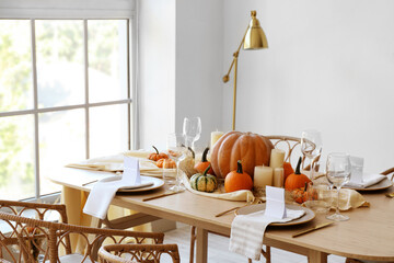 Dining table with pumpkins near window in room