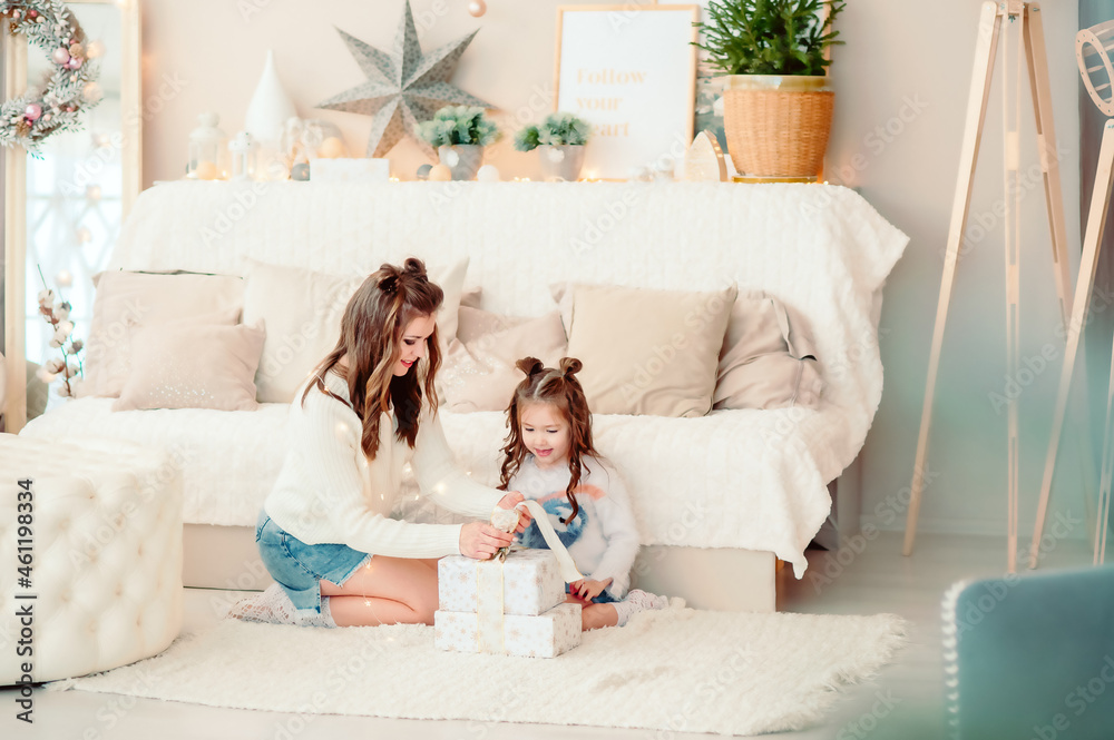mom and daughter are looking at New Year's gifts, sitting in a bright, beautiful room mom and daughter are looking at New Year's gifts, sitting in a bright, beautiful room