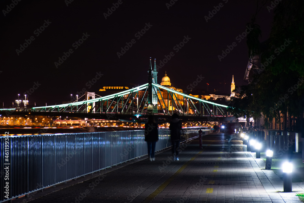 Obraz premium Budapest at night, two people walk along the Danube embankment.
